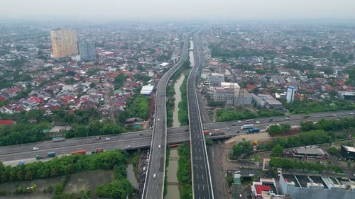 Aerial view of busy toll road crossing dense city area with bridges