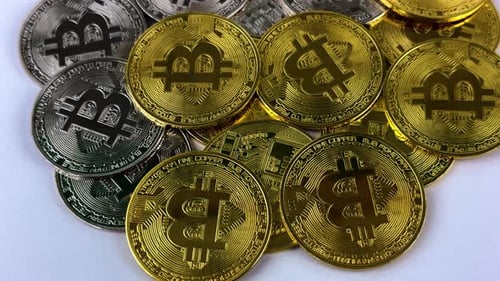 Pile of silver and gold bitcoins rotate on a white surface