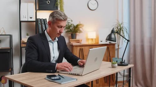Caucasian Young Businessman in Suit Opens Laptop and Start Working on Project at Home Office Desk
