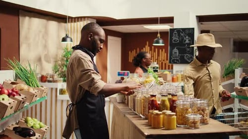 Merchant with Apron Placing Bulk Items on Shelves at Eco Store