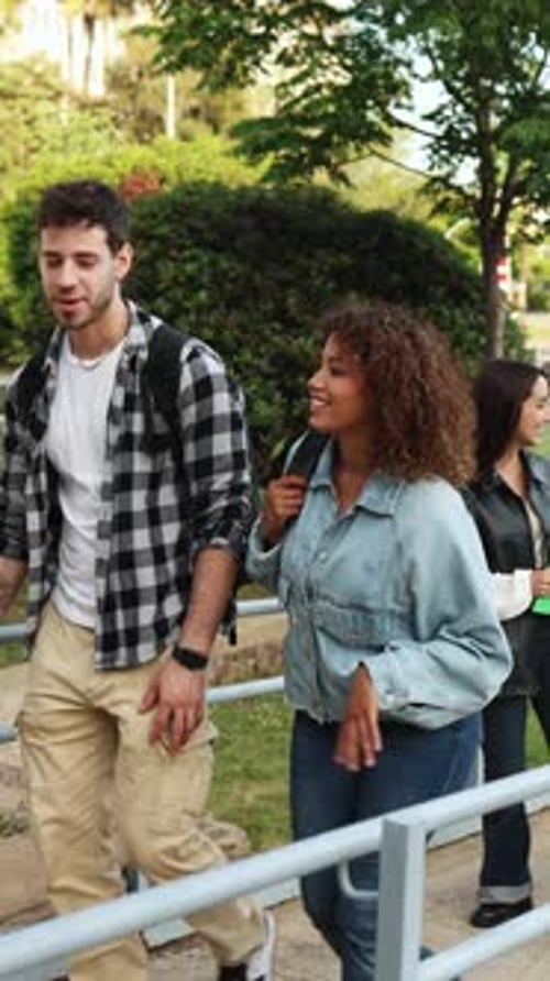 Diverse students walk and laugh on a college campus, holding books and backpacks
