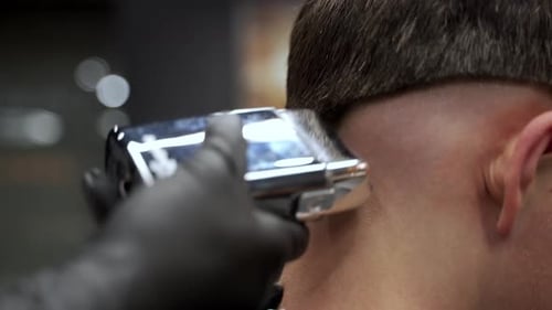 Professioneller Friseur schneidet Kunden im Salon die Haare, scharfe, detaillierte Nahaufnahme einer Präzisions-Haarschneidemaschine