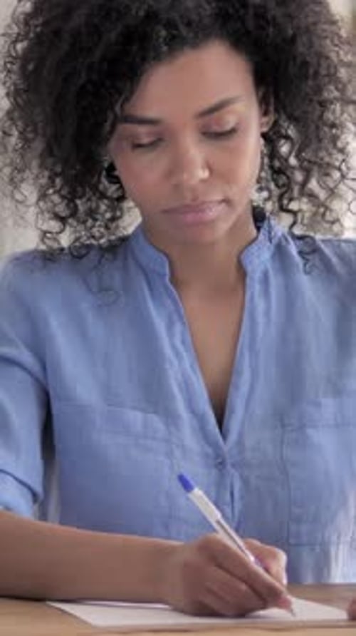Focused Woman Writes Carefully on Paper Indoors