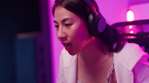 Close-up Young Asia female sit on gaming chair wear headset focus concentration pc screen.