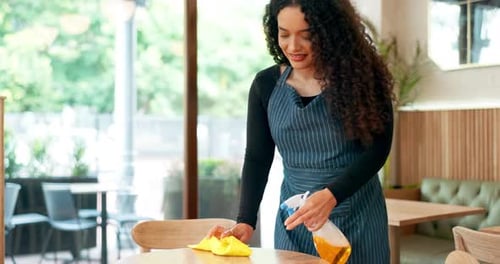 Waitress woman, spray and cleaning table for hygiene, bacteria and shine in coffee shop with smile