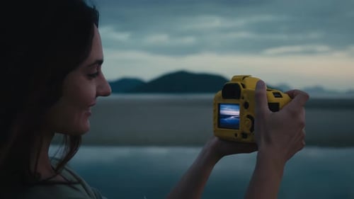 Woman Taking Pictures on Beach at Sunset