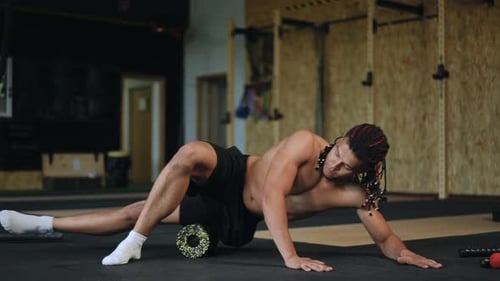 Man Using Foam Roller to Stretch in Gym