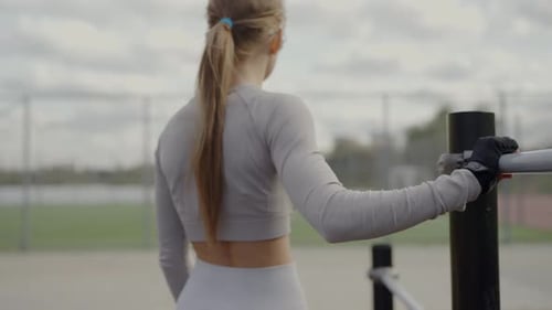 Woman Leaning on Bar in Outdoor Gym