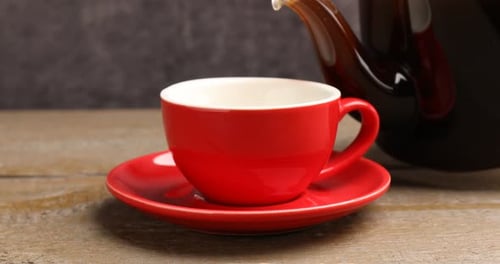 Aromatischen Kaffee in eine Tasse am Holztisch gießen, Nahaufnahme