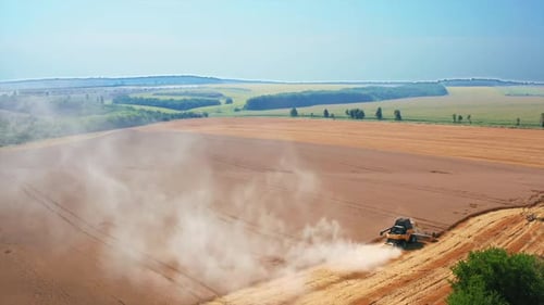 Yellow harvester combine mows the field of wheat. Another machine standing not far away. Top view.