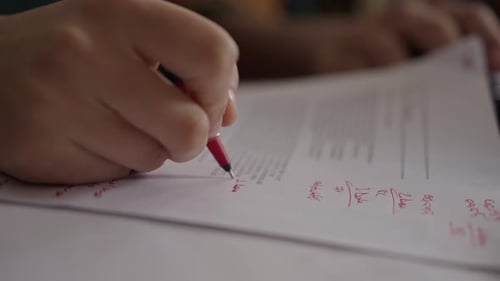 Close-Up of Taking Notes with a Red Ballpoint Pen in a Study Environment