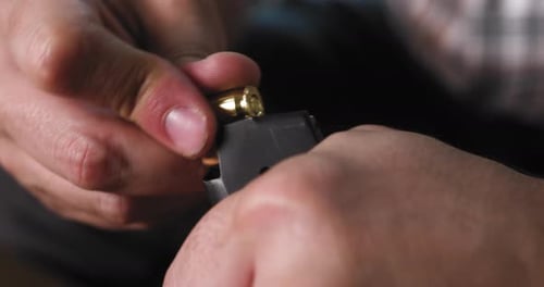 Mann lädt Munition in ein Pistolenmagazin