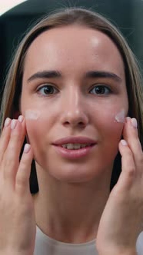 Close Up Portrait of Pretty Woman Using Moisturizing Face Cream and Smiling Looking at Camera