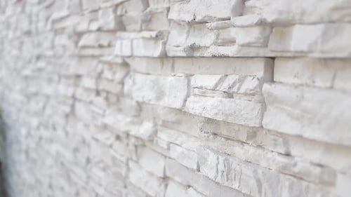 dolly shot detail of a white granite wall in a residential building outside.