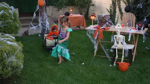 Children in Halloween costumes playing in a decorated backyard