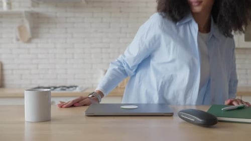 Woman Opens Laptop at Kitchen Counter for Work