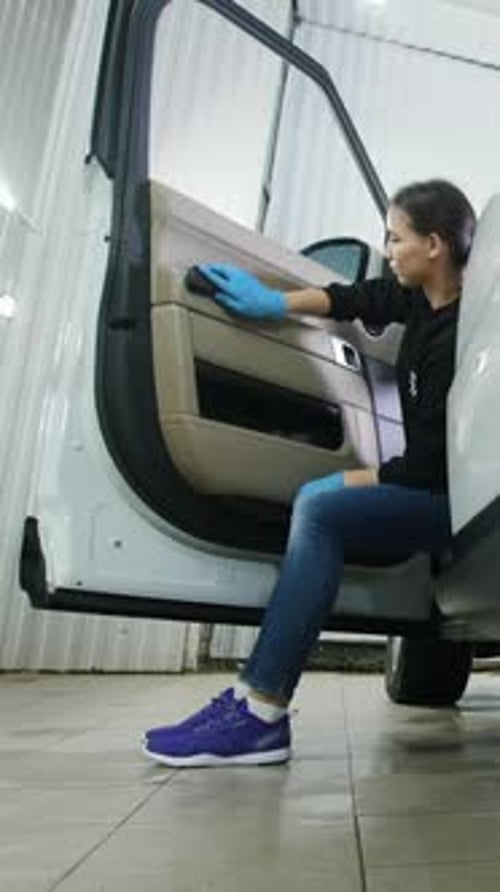 Female Worker Cleaning Car Interior with Brush