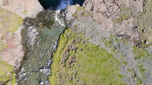 Aerial view of waterfall cascading into river, Iceland.