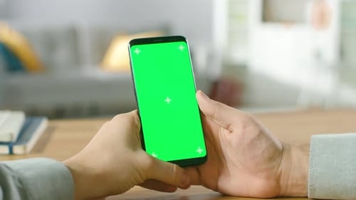 Close-up of a Man Holding Green Mock-up Screen Smartphone in His Hands. Using Wireless Device to Br