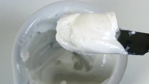 vue de mains gantées dans un laboratoire mélangeant un onguent blanc épais dans un mortier en porcelaine avec un ravageur