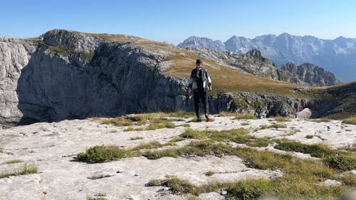 Ein Tourist mit Rucksack wandert entlang eines felsigen Bergplateaus vor der Kulisse wunderschöner