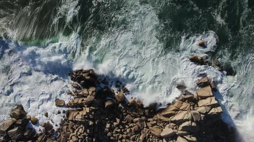 Topdown View of Powerful Storm Waves Rolling Onto the Rocky Shore