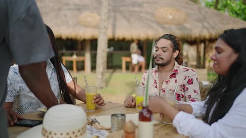 Diverse Friends Enjoy Meal at Outdoor Cafe LGBTQ Group Dines Chats in Tropical Setting Waiter