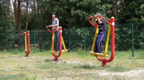Woman and Boy Using Outdoor Fitness Equipment