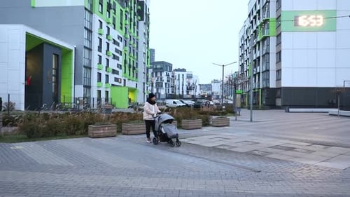 Strolling with a Stroller in a Modern Urban Area During Early Evening