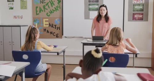 Happy diverse female teacher with tablet teaching schoolgirls in classroom at elementary school