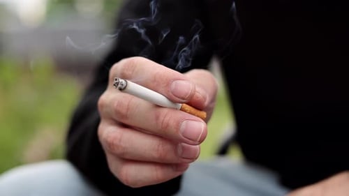 Cigarette in hand close up. Young man smoking a cigarette.