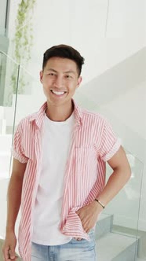 Vidéo verticale : homme asiatique avec un sourire éclatant debout dans les escaliers