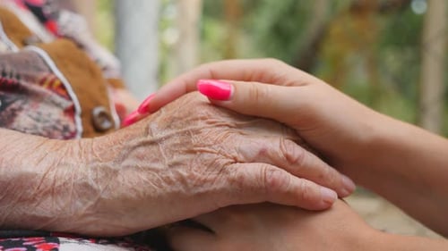 Tender Moment: Young Woman Holds Elderly Woman's Hand