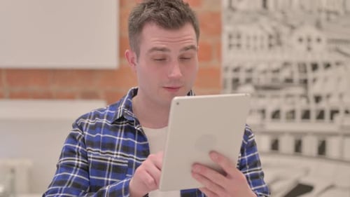 Young Man Cheers While Using Tablet Device