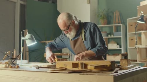 Adult Craftsman Carving Wood in Studio