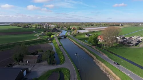 Aerial view of motorboat on winding river across green fields, Netherlands