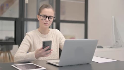 Young Adult Woman Using Smartphone at Desk