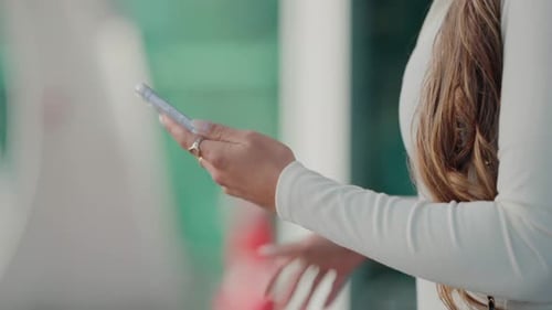 Woman in white using smartphone - Close up