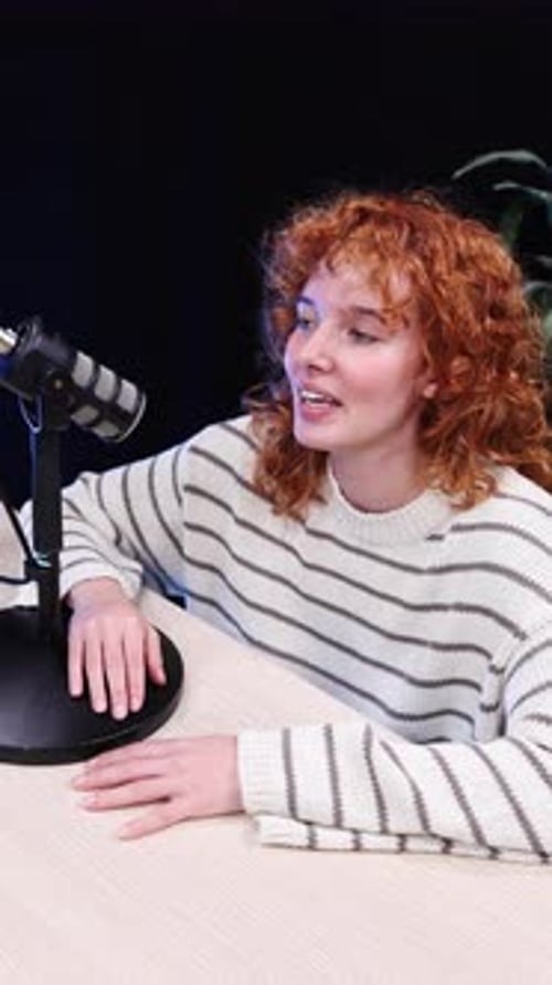 Woman at Table Speaking Into Microphone