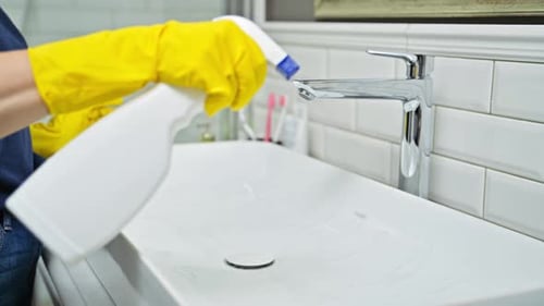 Person Cleaning a Sink with Cleaner and Cloth