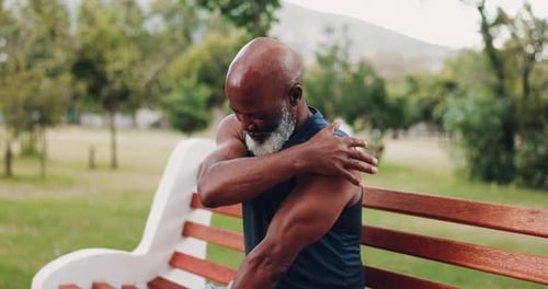 Senior Man Stretching Shoulders on Park Bench