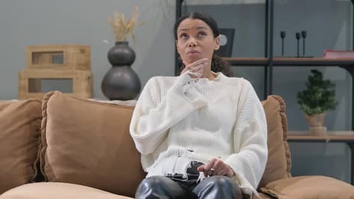 Thinking African Woman Sitting on Sofa at Home