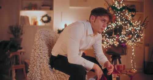 Pensive Young Man Sits in Christmas Setting