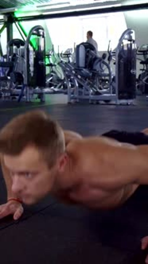 Determined Man Performing Pushups in a Modern Gym