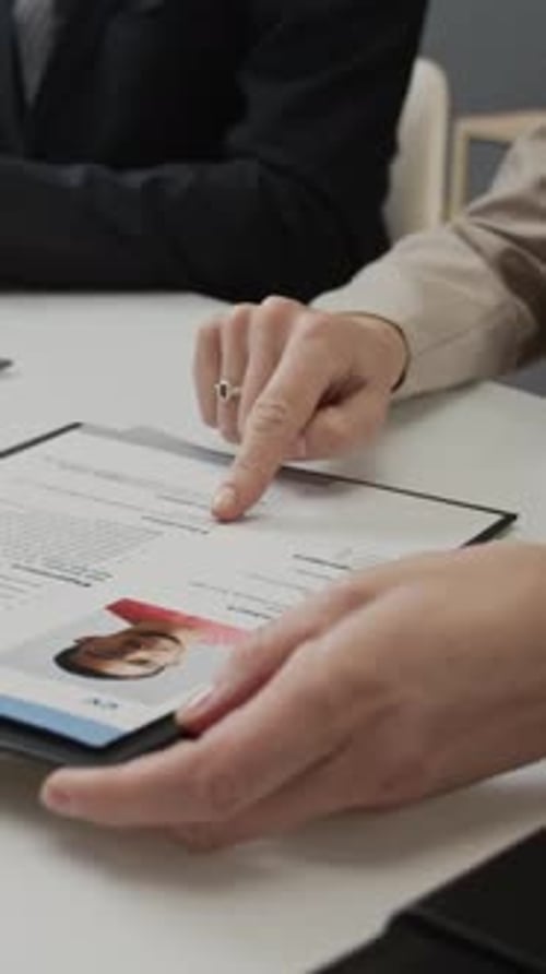 Vertical Close-up of Anonymous HR Manager Studying Application Form of Young Man