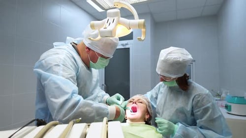Oral Surgeon Nurse Doing Medical Operation on Root Canals in Operating Room Dentist Puts Stitches on