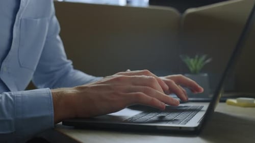 Focused businessman hands typing on laptop computer in modern office