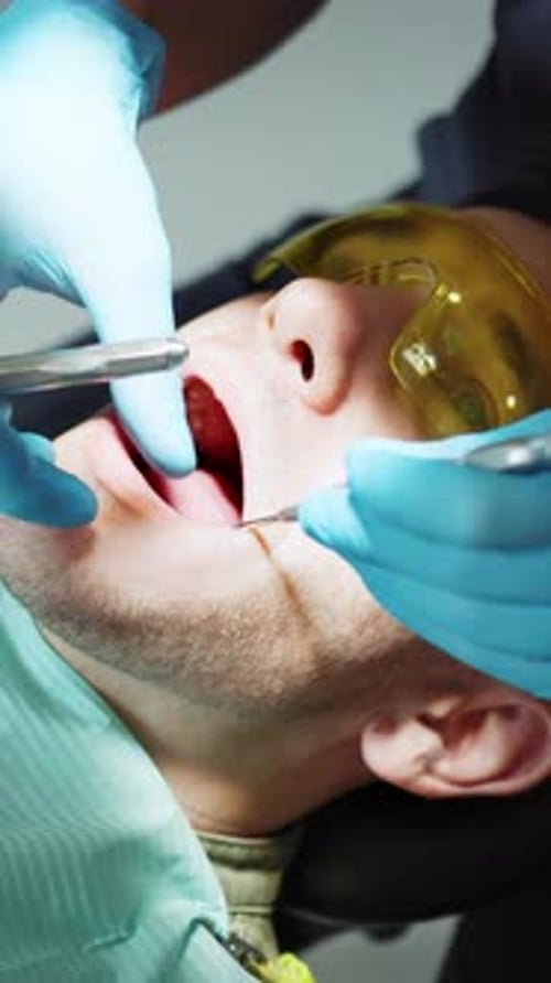 Footage of Caucasian Male Patient in Yellow Protective Glasses Getting Dental Treatment at Modern