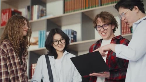 Group of diverse students collaborating on laptop in university library