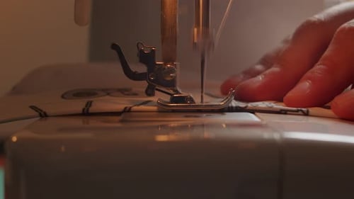 Side view close up of sewing machine foot and needle passing through fabric